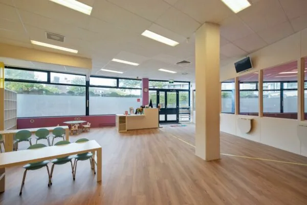 Moderne en lichte wachtruimte of binnenruimte in een kinderopvang aan de Koningin Julianalaan, met speelhoek, kinderstoelen en balie.